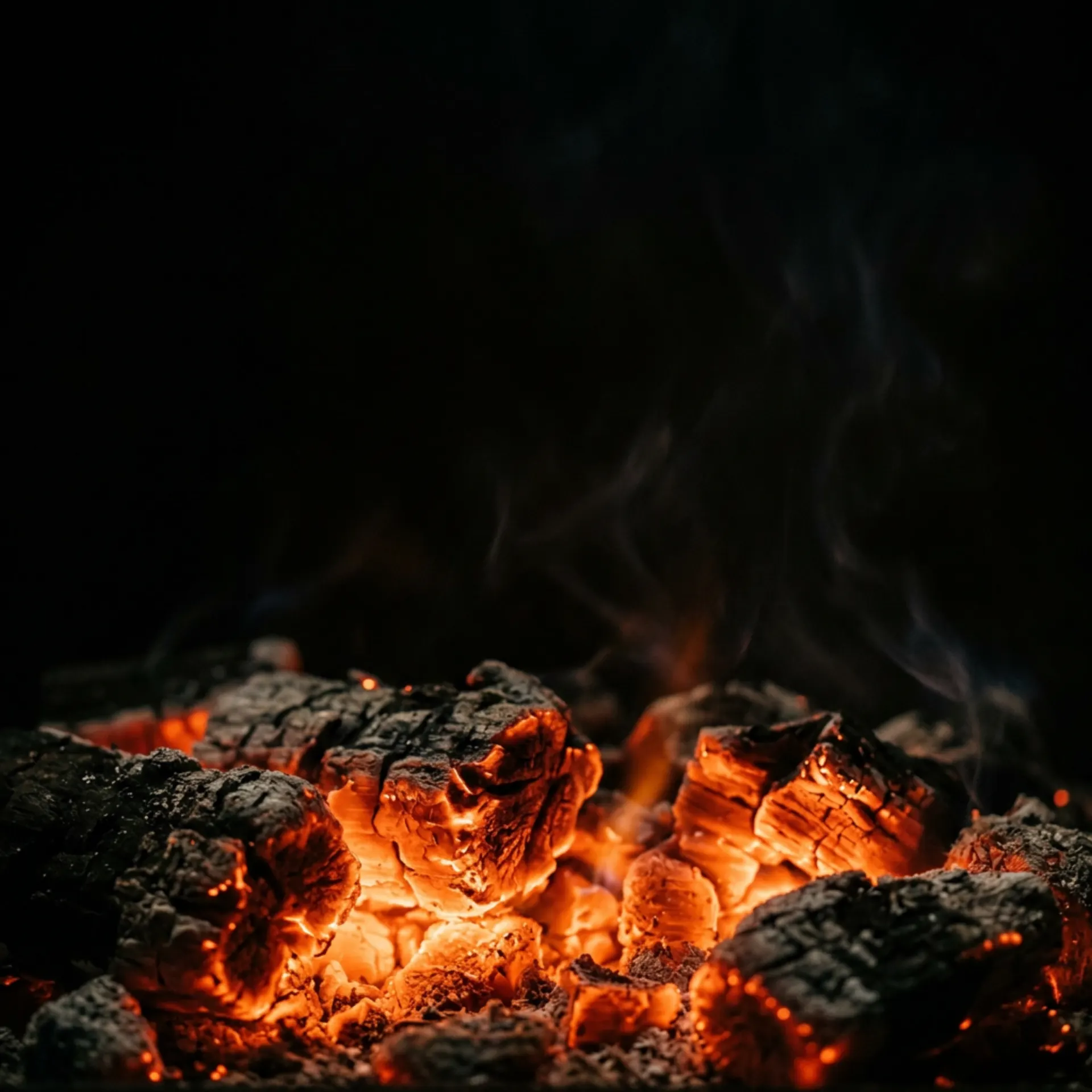 Oak coals glowing in the dark hearth of the asador